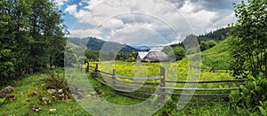 Ukraine rural countryside panorama. Wooden fence and house on Carpathian meadow