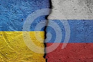 Ukraine and Russia - Cracked concrete wall painted with a Ukrainian flag on the left and a Russian flag on the right stock photo