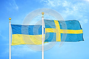 Ukraine and Sweden two flags on flagpoles and blue sky