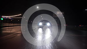 Ukraine, Zaporozhye - Decenber 25, 2022: car drives high speed through rain. Headlights break through heavy rain