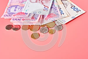 Ukrainian banknotes and coins on pink background. Payment of pensions, salaries