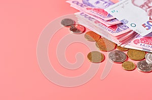 Ukrainian banknotes and coins on pink background. Payment of pensions, salaries