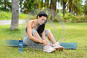 Ukrainian beautiful woman tying shoes laces after doing yoga on the map outside