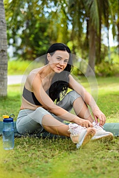 Ukrainian beautiful woman tying shoes laces after doing yoga on the map outside