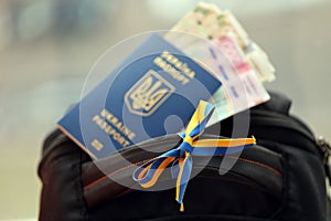 Ukrainian biometrical passport and UAH money bills on touristic backpack