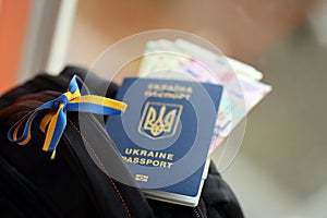 Ukrainian biometrical passport and UAH money bills on touristic backpack