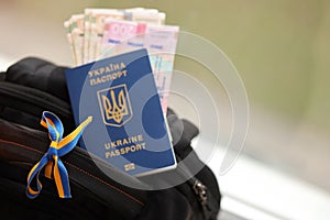 Ukrainian biometrical passport and UAH money bills on touristic backpack