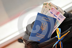 Ukrainian biometrical passport and UAH money bills on touristic backpack