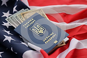 Ukrainian biometrical passport and US dollar bills on folded waving flag of United States of America