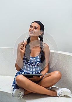 Ukrainian brunette woman illustrator and artist thinking about her electronical drawing in the tablet