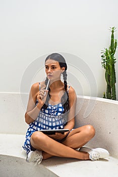 Ukrainian brunette woman illustrator and artist thinking about her electronical drawing in the tablet