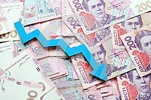 Ukrainian cash hryvnia and down arrow. The economic crisis and inflation
