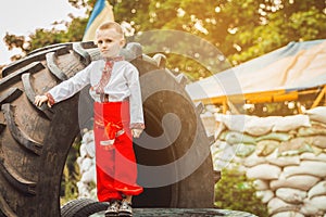 Ukrainian child boy stands on roadblock near tire against background of sandbags