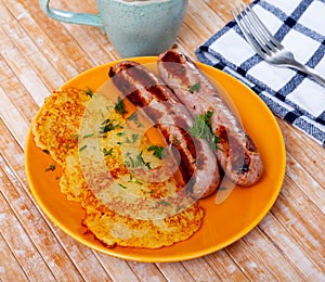 Ukrainian deruny, potato flapjacks, with fried sausages on plate