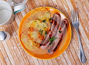 Ukrainian deruny, potato flapjacks, with fried sausages on plate