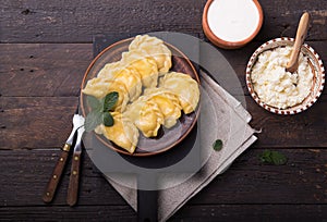 Ukrainian dumplings, pierogi or pyrohy, varenyky, vareniki, served with cottage cheese on board. National Russian cuisine, natural