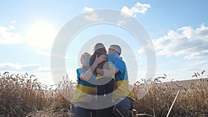 Ukrainian family mother, father and daughter hugging in a wheat field. Sunny day.