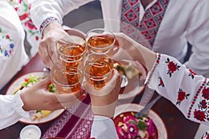 Ukrainian family in traditional closes has a dinner. Ukrainian culture. Family eating and clang glasses together.