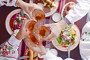 Ukrainian family in traditional closes has a dinner. Ukrainian culture. Family eating and clang glasses together.