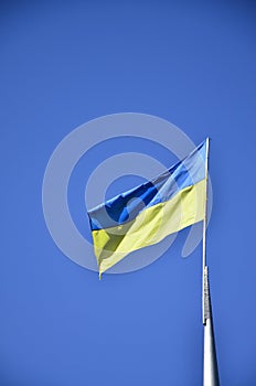 Ukrainian flag against the blue cloudless sky. The official flag of the Ukrainian state includes yellow and blue color