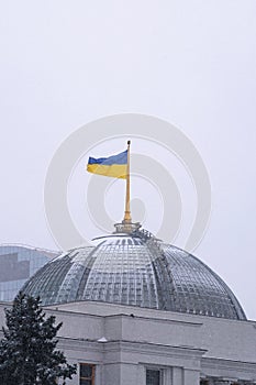 Ukrainian flag waving over Parliament Verkhovna Rada of Ukraine in Kiev, Ukraine. Snowfall morning