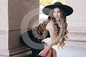 Ukrainian girl in a black dress outdoors in a hat