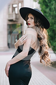 Ukrainian girl in a black dress outdoors in a hat