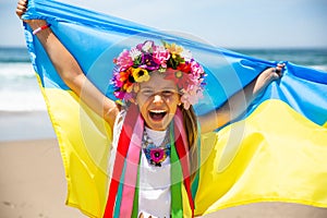 Ukrainian girl carries blue and yellow flag of Ukraine fluttering on the blue sky background