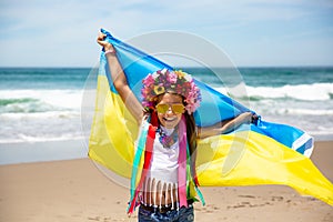 Ukrainian girl carries blue and yellow flag of Ukraine fluttering on the blue sky background