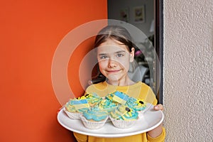Ukrainian girl for whom neighbors brought cupcakes with cream in yellow and blue colors for brunch