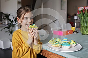 Ukrainian girl for whom neighbors brought cupcakes with cream in yellow and blue colors for brunch