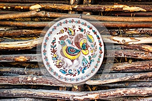 Ukrainian handmade earthenware utensil. Painted plate on wooden wall. Souvenirs From Ukraine in ethnic style.