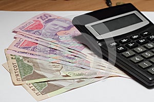 Ukrainian hryvnia and calculator on wooden table