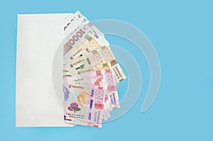 Ukrainian hryvnia in a white envelope isolated on a blue background. Copy of space. 200, 500, 1000 hryvnias. Financial concept.