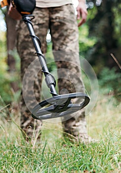 Ukrainian Military sapper with a metal detector in the field. Explosive Ordnance Disposal Officer