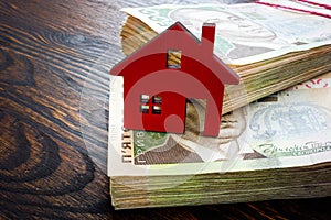 Ukrainian money hryvnia and model of home. Buy property or mortgage in Ukraine.