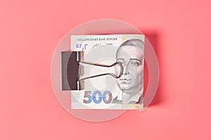 Ukrainian money with metal clip on pink background. Payment of pensions, salaries