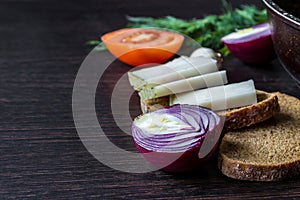 Ukrainian national food is lard salo with bread with red onions on the background of the tomato with garlic on wooden table.
