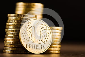 Ukrainian one hryvnia coin and gold money on the desk