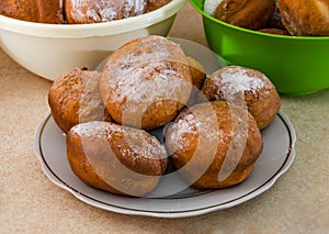 Ukrainian round donuts in a plate on the table. Lots of delicious donuts with powdered sugar.