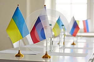 Ukrainian and Russian flags on table at negotiations on stopping war and restoring peace