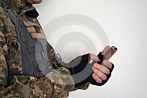 Ukrainian soldier in military pixel unform and bulletproof vest jacket with banner of flag of Ukraine tapping on smartphone