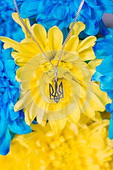 Ukrainian symbol trident on the background of blue and yellow chrysanthemums. War in Ukraine 2022. State coat of arms of