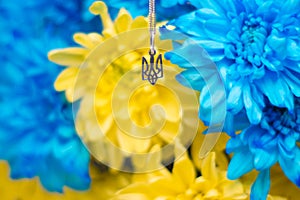 Ukrainian symbol trident on the background of blue and yellow chrysanthemums. War in Ukraine 2022. State coat of arms of