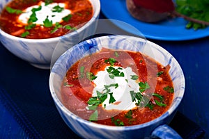 Ukrainian traditional borsch. Russian vegetarian red soup in blue bowl on blue wooden background. Borscht, borshch with beet. Tw