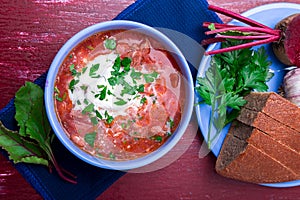 Ukrainian traditional borsch. Russian vegetarian red soup in blue bowl on red wooden background. Borscht, borshch with beet. To