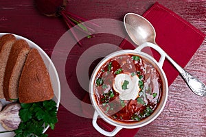 Ukrainian traditional borsch. Russian vegetarian red soup in white bowl on red wooden background. Top view. Borscht, borshch wit