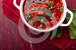 Ukrainian traditional borsch. Russian vegetarian red soup in white bowl on red wooden background. Top view. Borscht, borshch wit