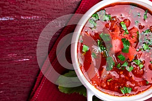 Ukrainian traditional borsch. Russian vegetarian red soup in white bowl on red wooden background. Top view. Borscht, borshch wit