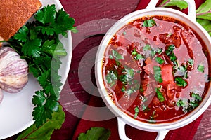 Ukrainian traditional borsch. Russian vegetarian red soup in white bowl on red wooden background. Top view. Borscht, borshch wit